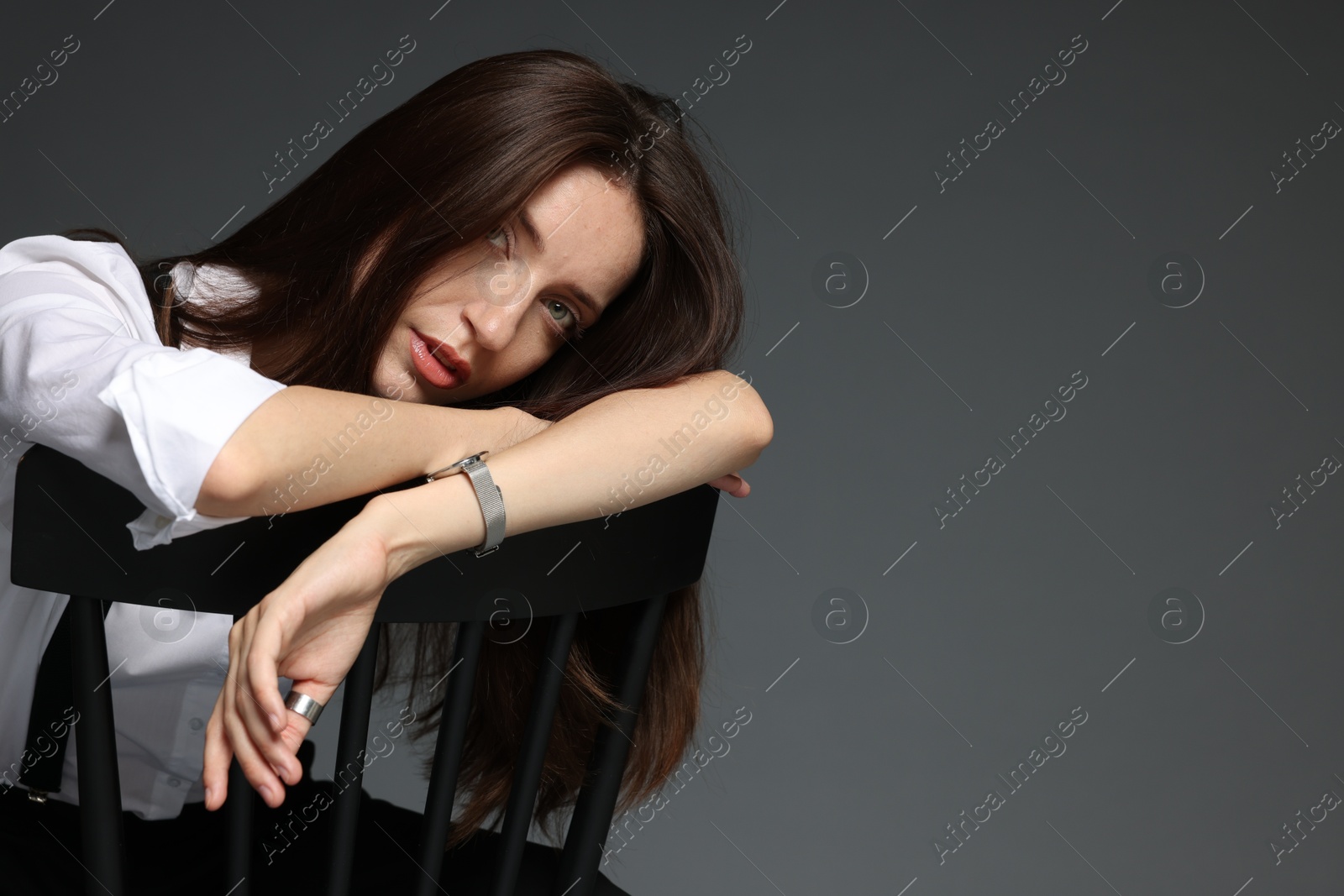 Beautiful woman in stylish outfit sitting on chair against grey background, space for text Photo of Beautiful woman in stylish outfit sitting on chair against grey background, space for text