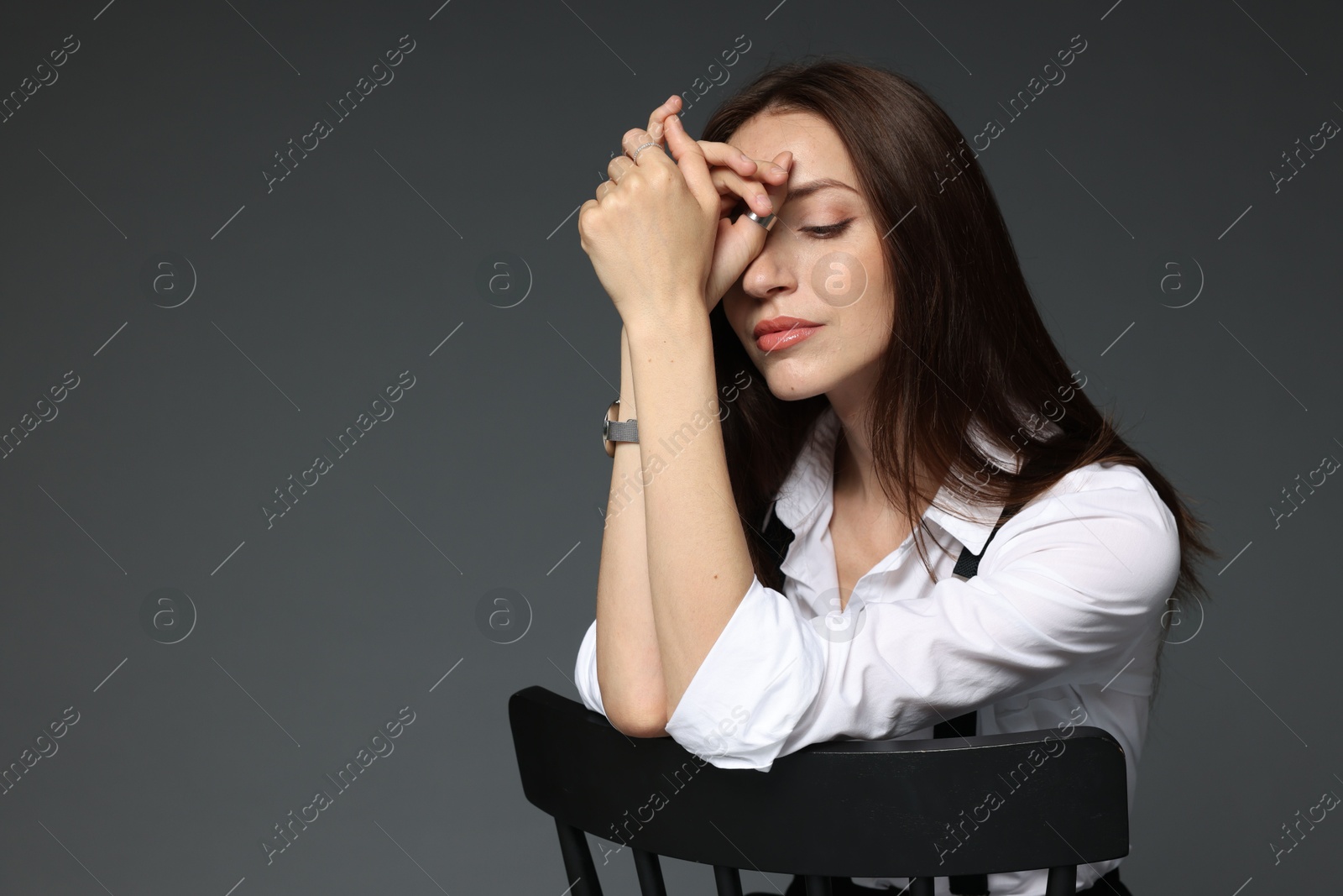 Beautiful woman in stylish outfit sitting on chair against grey background, space for text Photo of Beautiful woman in stylish outfit sitting on chair against grey background, space for text