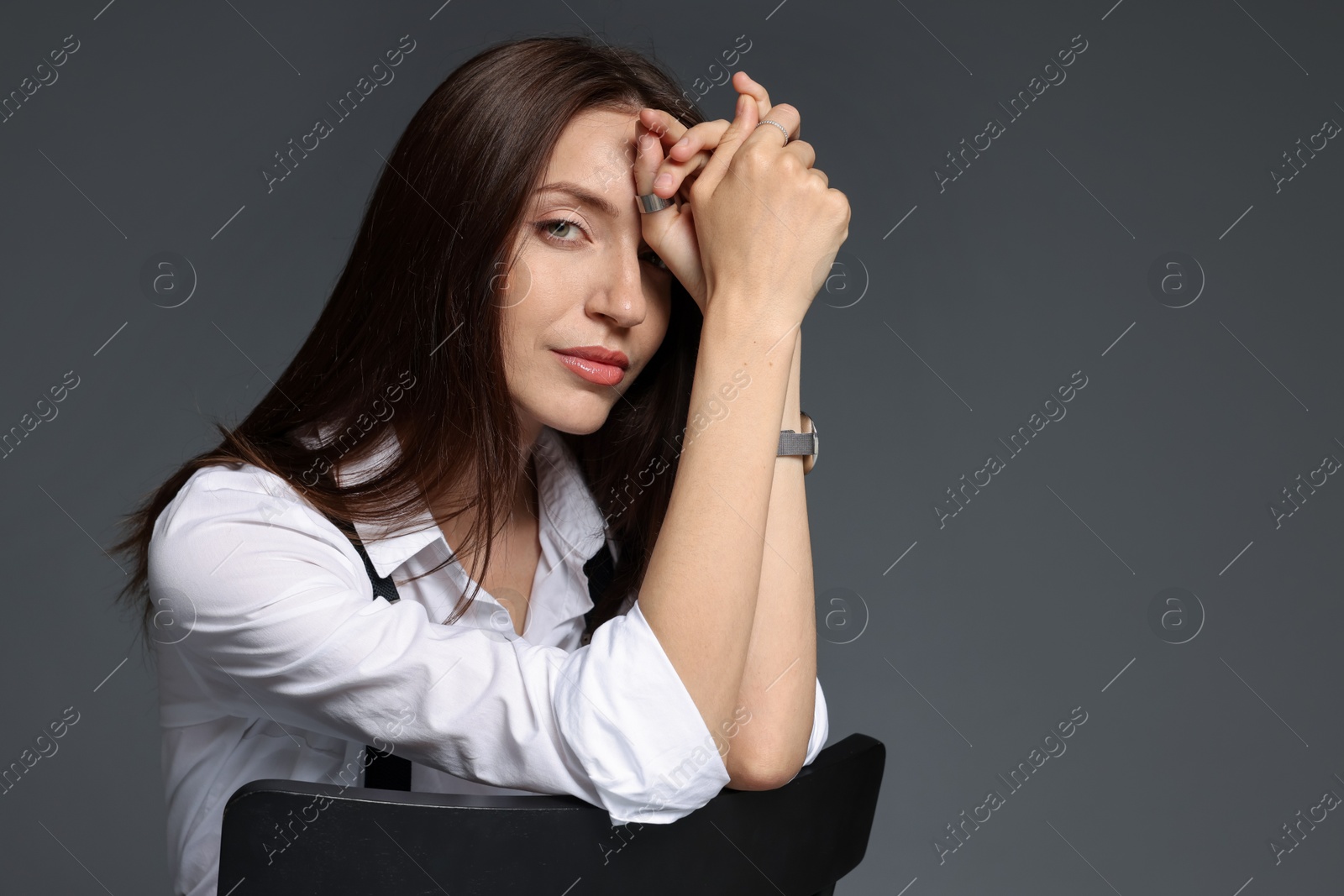 Beautiful woman in stylish outfit sitting on chair against grey background, space for text Photo of Beautiful woman in stylish outfit sitting on chair against grey background, space for text
