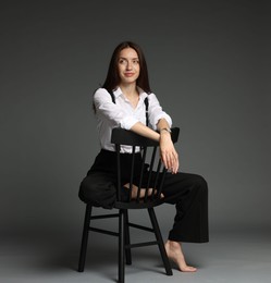 Photo of Beautiful woman in stylish outfit sitting on chair against grey background