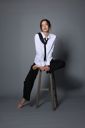 Photo of Beautiful woman in stylish outfit sitting on chair against light grey background