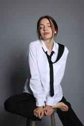 Photo of Beautiful woman in stylish outfit sitting on chair against light grey background