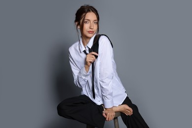 Photo of Beautiful woman in stylish outfit sitting on chair against light grey background