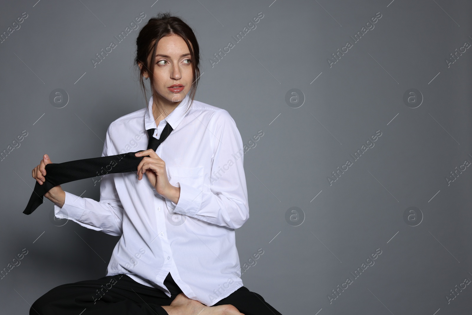 Beautiful woman in stylish outfit sitting on chair against light grey background, space for text Photo of Beautiful woman in stylish outfit sitting on chair against light grey background, space for text