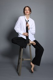 Photo of Beautiful woman in stylish outfit sitting on chair against light grey background