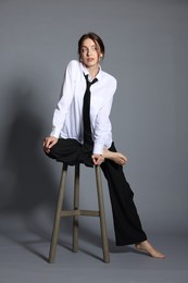Photo of Beautiful woman in stylish outfit sitting on chair against light grey background
