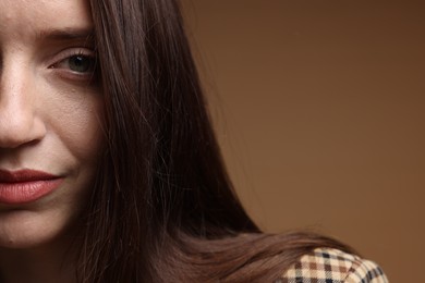 Photo of Beautiful woman in stylish outfit on brown background, closeup. Space for text