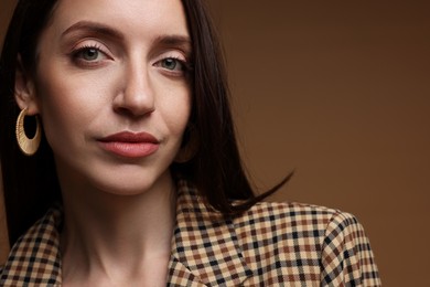 Photo of Beautiful woman in stylish outfit on brown background, closeup. Space for text