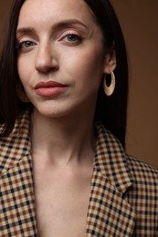 Photo of Beautiful woman in stylish outfit on brown background, closeup