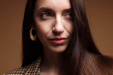 Photo of Beautiful woman in stylish outfit on brown background, closeup
