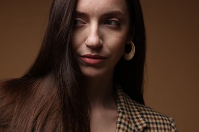 Photo of Beautiful woman in stylish outfit on brown background, closeup