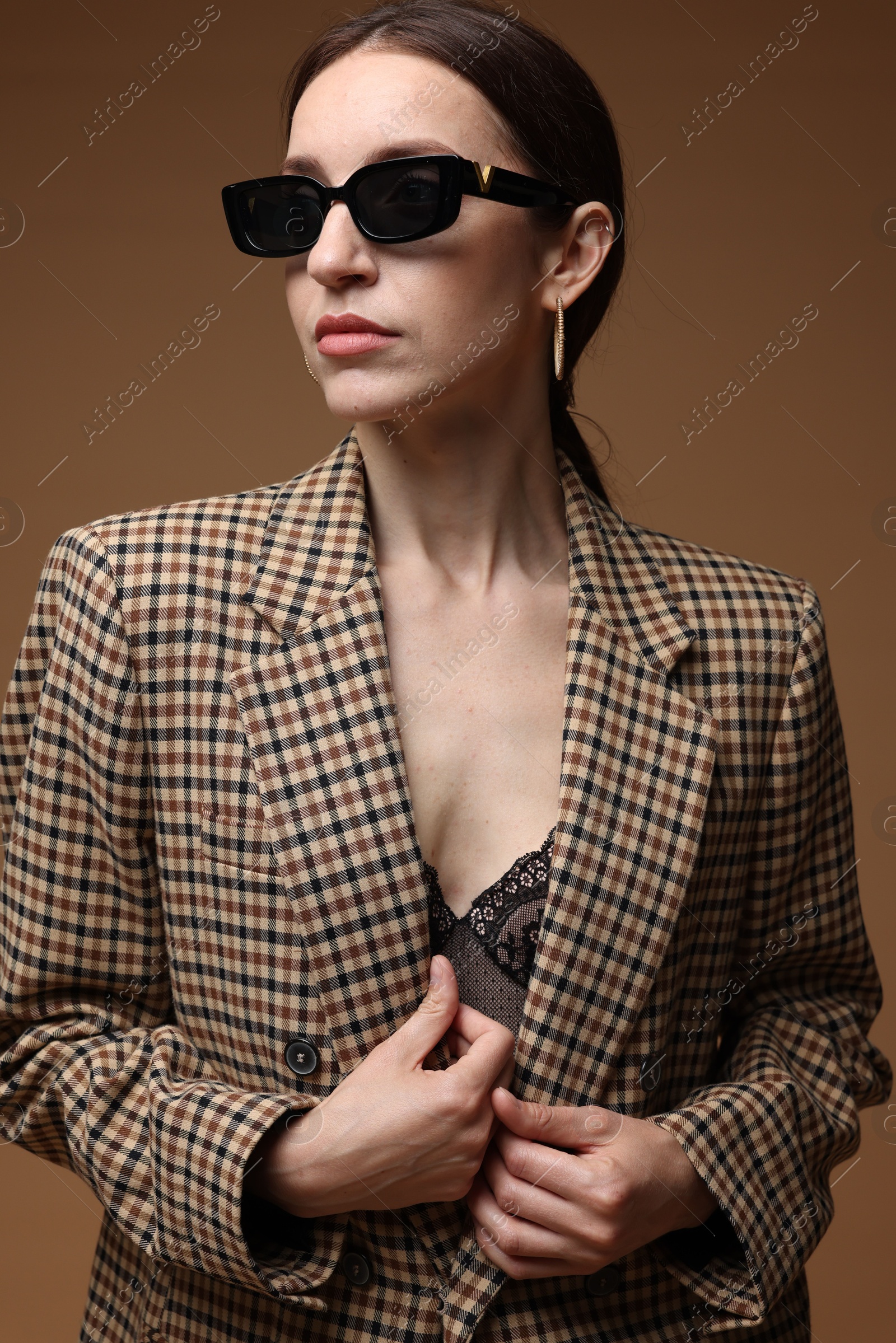 Portrait of beautiful woman in stylish outfit on brown background Photo of Portrait of beautiful woman in stylish outfit on brown background
