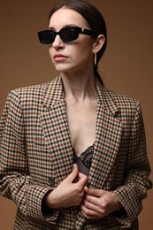 Photo of Portrait of beautiful woman in stylish outfit on brown background