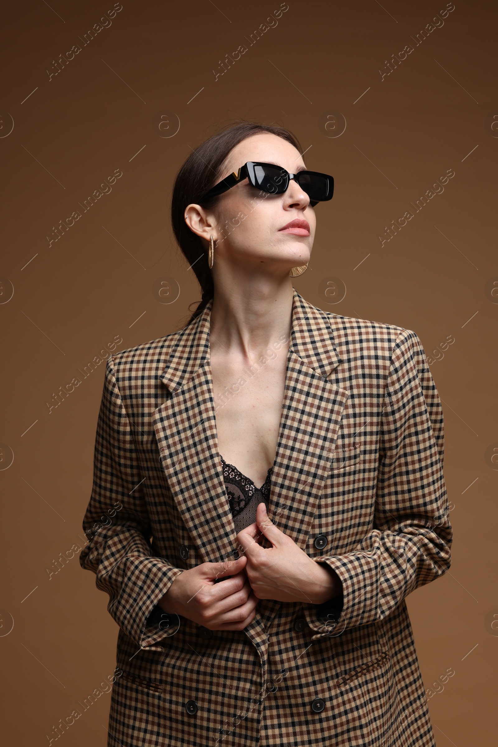 Portrait of beautiful woman in stylish outfit on brown background Photo of Portrait of beautiful woman in stylish outfit on brown background