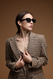 Photo of Portrait of beautiful woman in stylish outfit on brown background