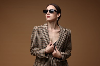 Photo of Portrait of beautiful woman in stylish outfit on brown background
