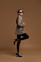 Photo of Full-length portrait of beautiful woman in stylish outfit on brown background
