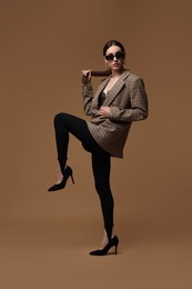 Photo of Full-length portrait of beautiful woman in stylish outfit on brown background