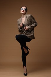 Photo of Full-length portrait of beautiful woman in stylish outfit on brown background