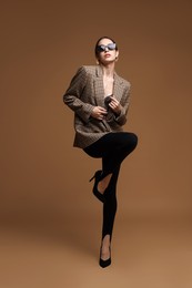 Photo of Full-length portrait of beautiful woman in stylish outfit on brown background
