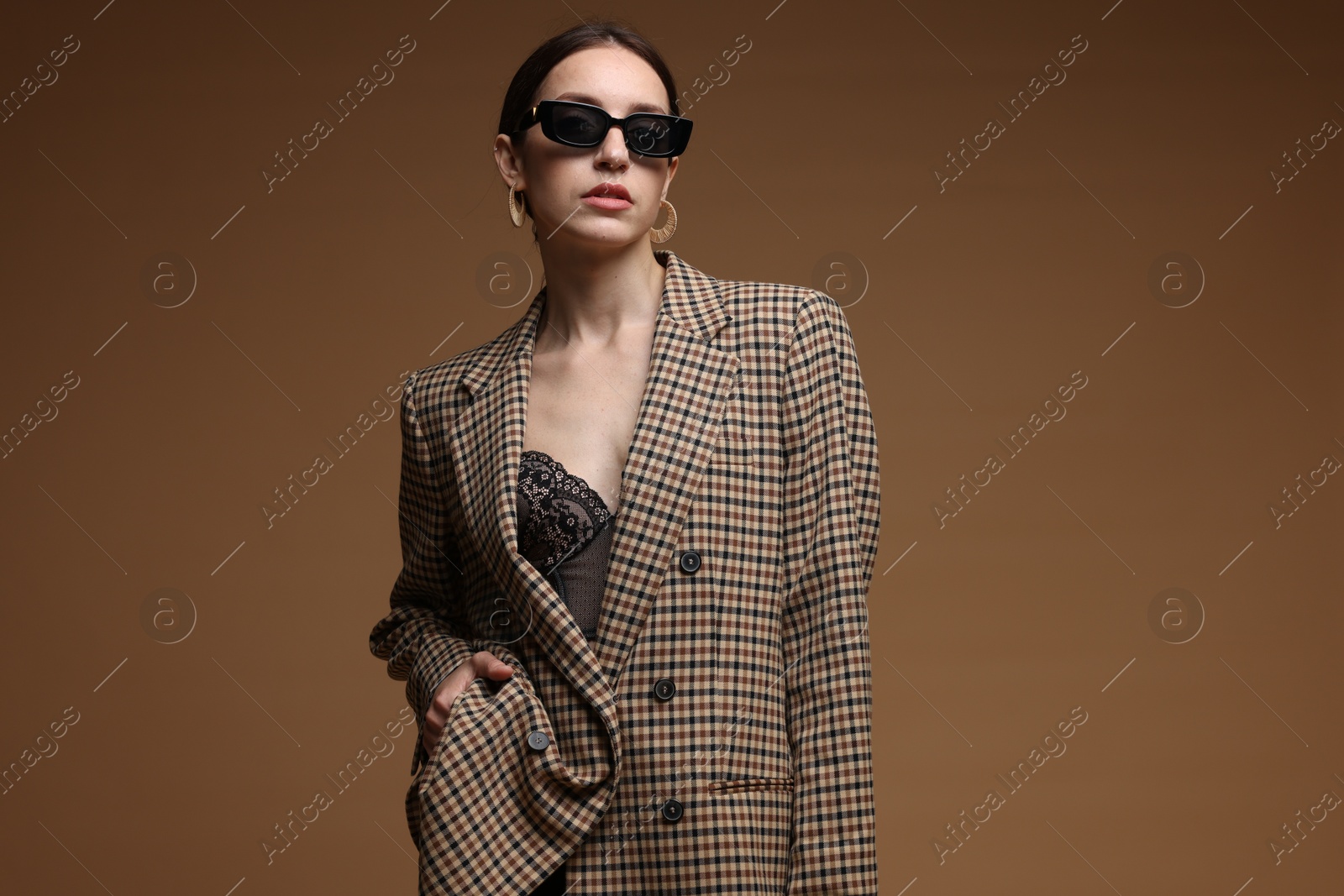 Portrait of beautiful woman in stylish outfit on brown background Photo of Portrait of beautiful woman in stylish outfit on brown background