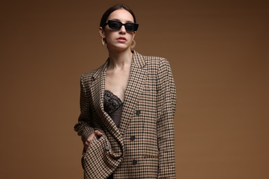 Photo of Portrait of beautiful woman in stylish outfit on brown background