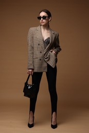 Photo of Full-length portrait of beautiful woman in stylish outfit on brown background