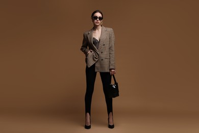 Photo of Full-length portrait of beautiful woman in stylish outfit on brown background