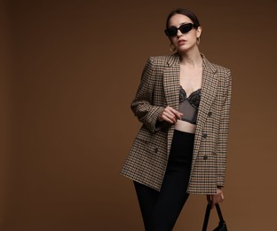 Photo of Portrait of beautiful woman in stylish outfit on brown background, space for text