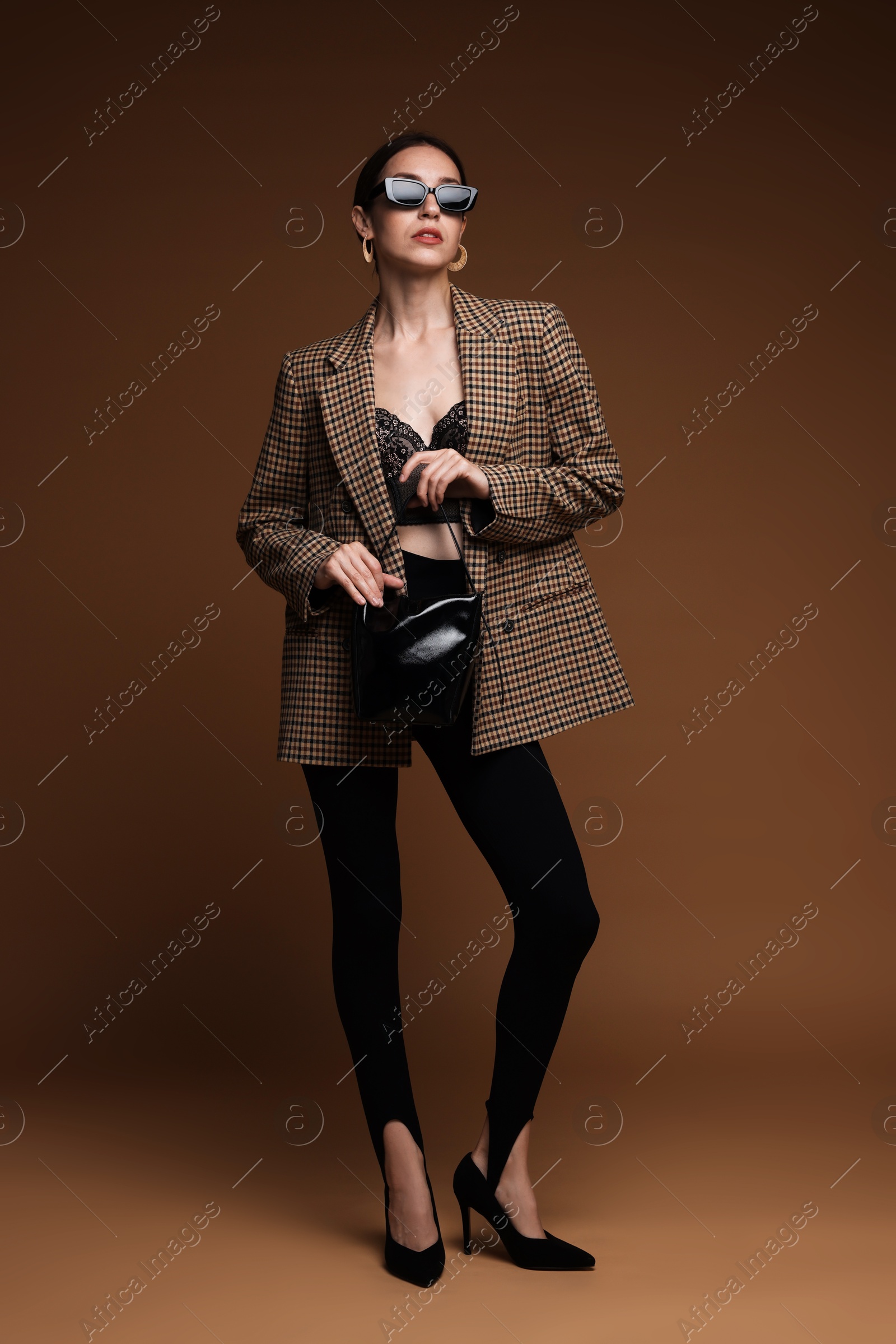Full-length portrait of beautiful woman in stylish outfit on brown background Photo of Full-length portrait of beautiful woman in stylish outfit on brown background