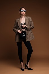Photo of Full-length portrait of beautiful woman in stylish outfit on brown background