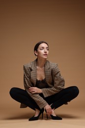 Photo of Full-length portrait of beautiful woman in stylish outfit on beige background