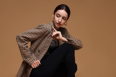Photo of Portrait of beautiful woman in stylish outfit on beige background