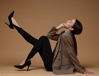 Photo of Full-length portrait of beautiful woman in stylish outfit on beige background