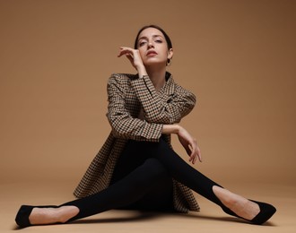 Photo of Full-length portrait of beautiful woman in stylish outfit on beige background