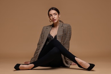 Photo of Full-length portrait of beautiful woman in stylish outfit on beige background