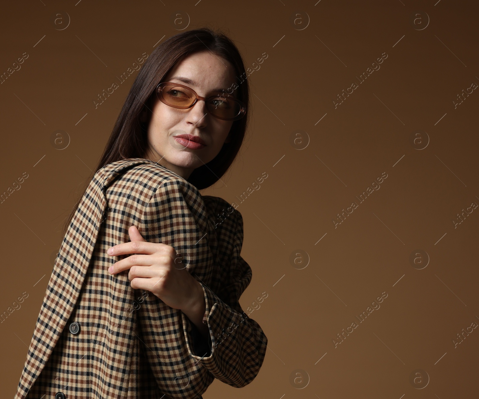 Portrait of beautiful woman in stylish outfit on brown background, space for text Photo of Portrait of beautiful woman in stylish outfit on brown background, space for text