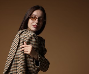 Photo of Portrait of beautiful woman in stylish outfit on brown background, space for text
