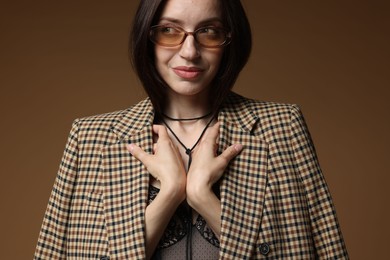 Photo of Portrait of beautiful woman in stylish outfit on brown background
