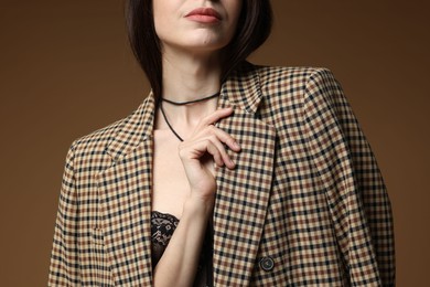 Photo of Beautiful woman in stylish outfit on brown background, closeup