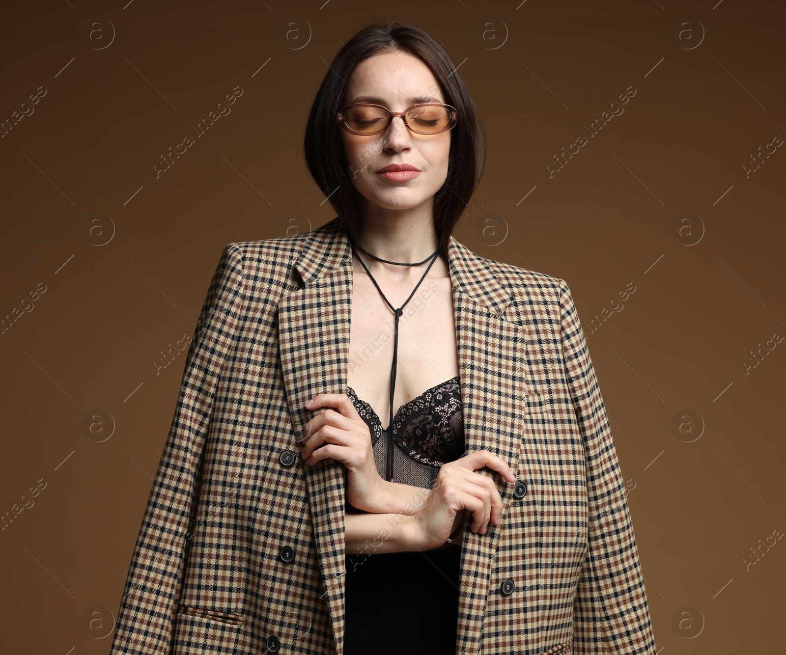 Portrait of beautiful woman in stylish outfit on brown background Photo of Portrait of beautiful woman in stylish outfit on brown background
