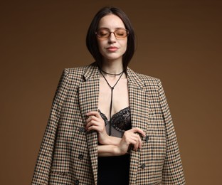 Photo of Portrait of beautiful woman in stylish outfit on brown background