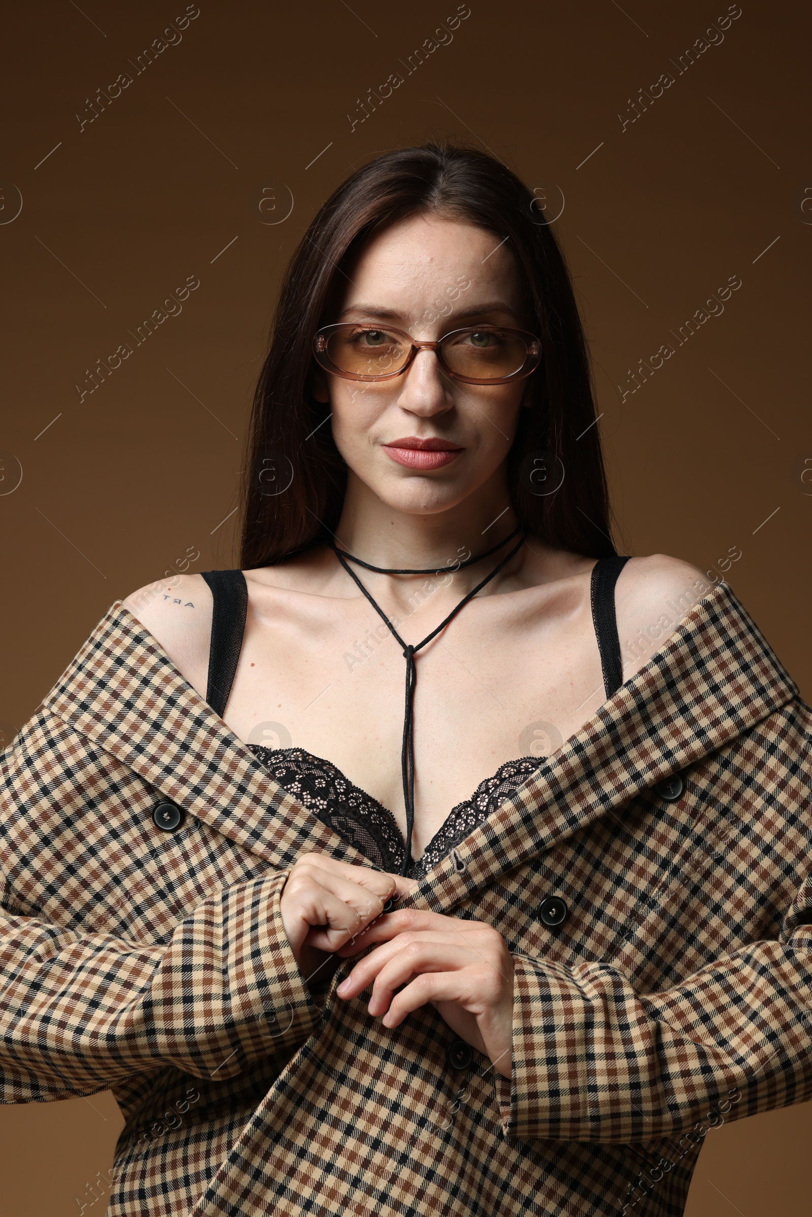 Portrait of beautiful woman in stylish outfit on brown background Photo of Portrait of beautiful woman in stylish outfit on brown background