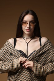 Photo of Portrait of beautiful woman in stylish outfit on brown background