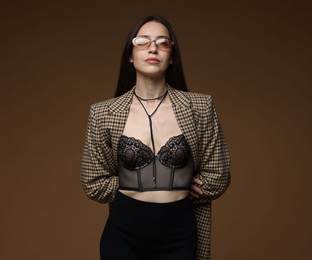 Photo of Portrait of beautiful woman in stylish outfit on brown background