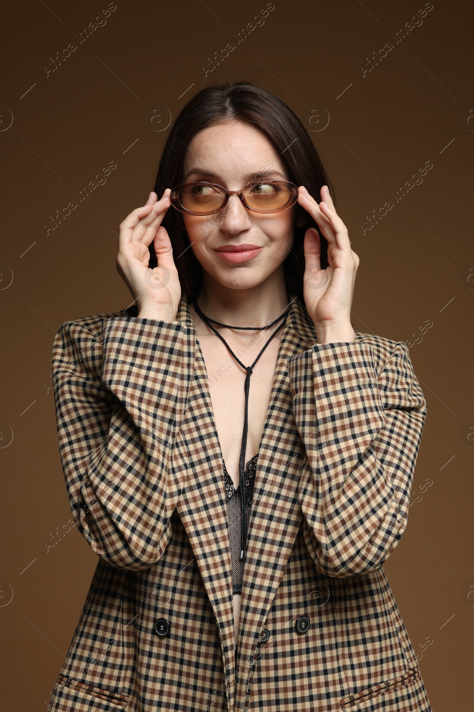 Portrait of beautiful woman in stylish outfit on brown background Photo of Portrait of beautiful woman in stylish outfit on brown background