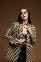 Photo of Portrait of beautiful woman in stylish outfit on brown background