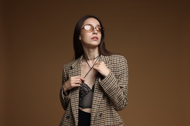 Photo of Portrait of beautiful woman in stylish outfit on brown background