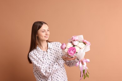 Photo of Woman with beautiful bouquet of peonies on dark beige background