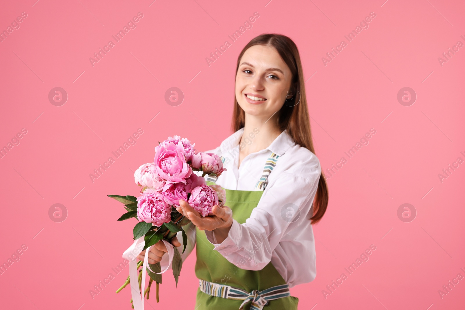 Florist with beautiful peonies on pink background Photo of Florist with beautiful peonies on pink background